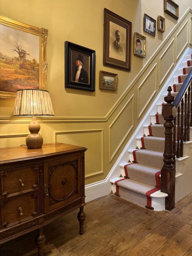 butter yellow hallway with brown wooden floor and dark brown staircase